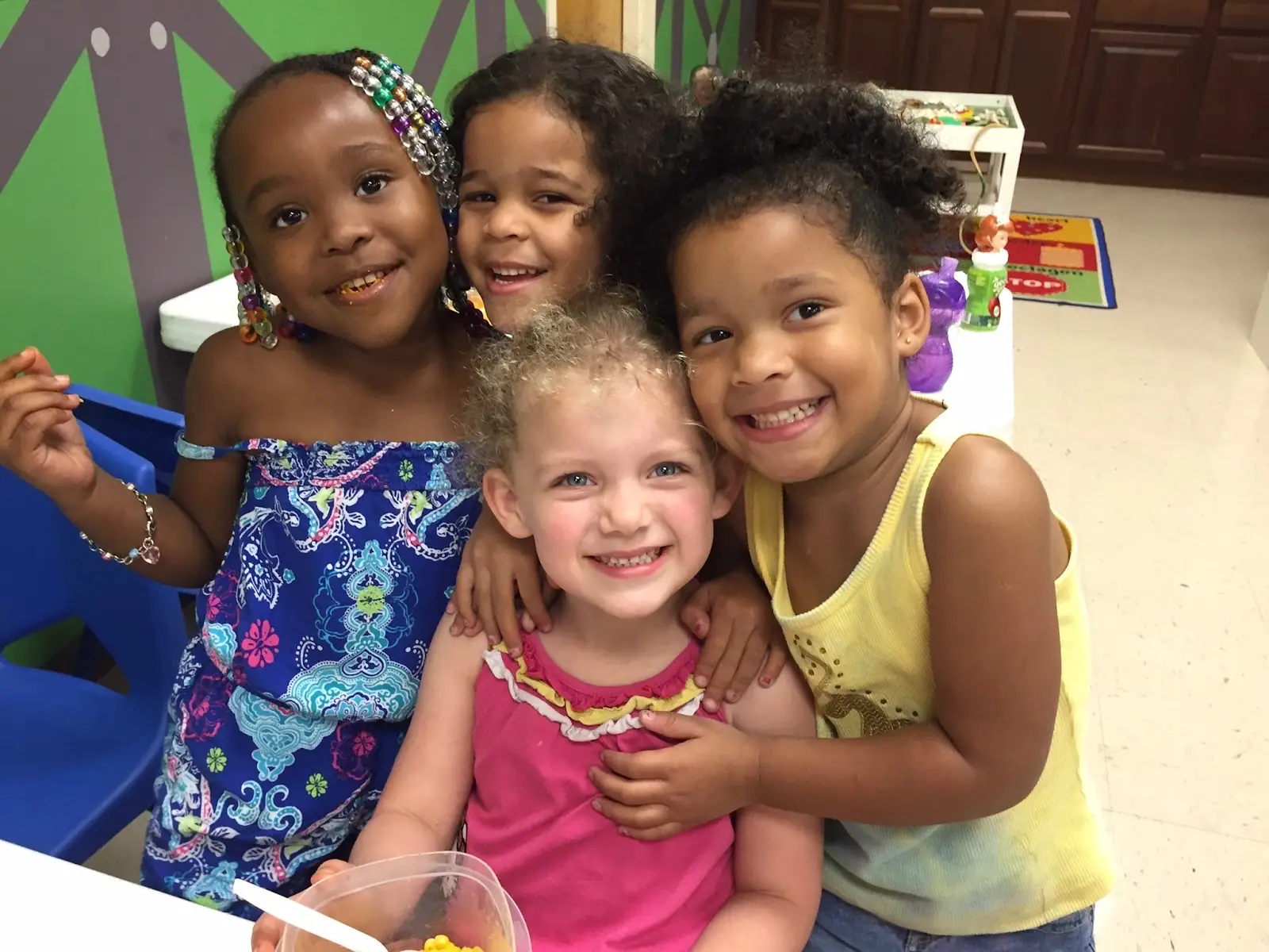 Four Early Learning Center friends hugging and smiling