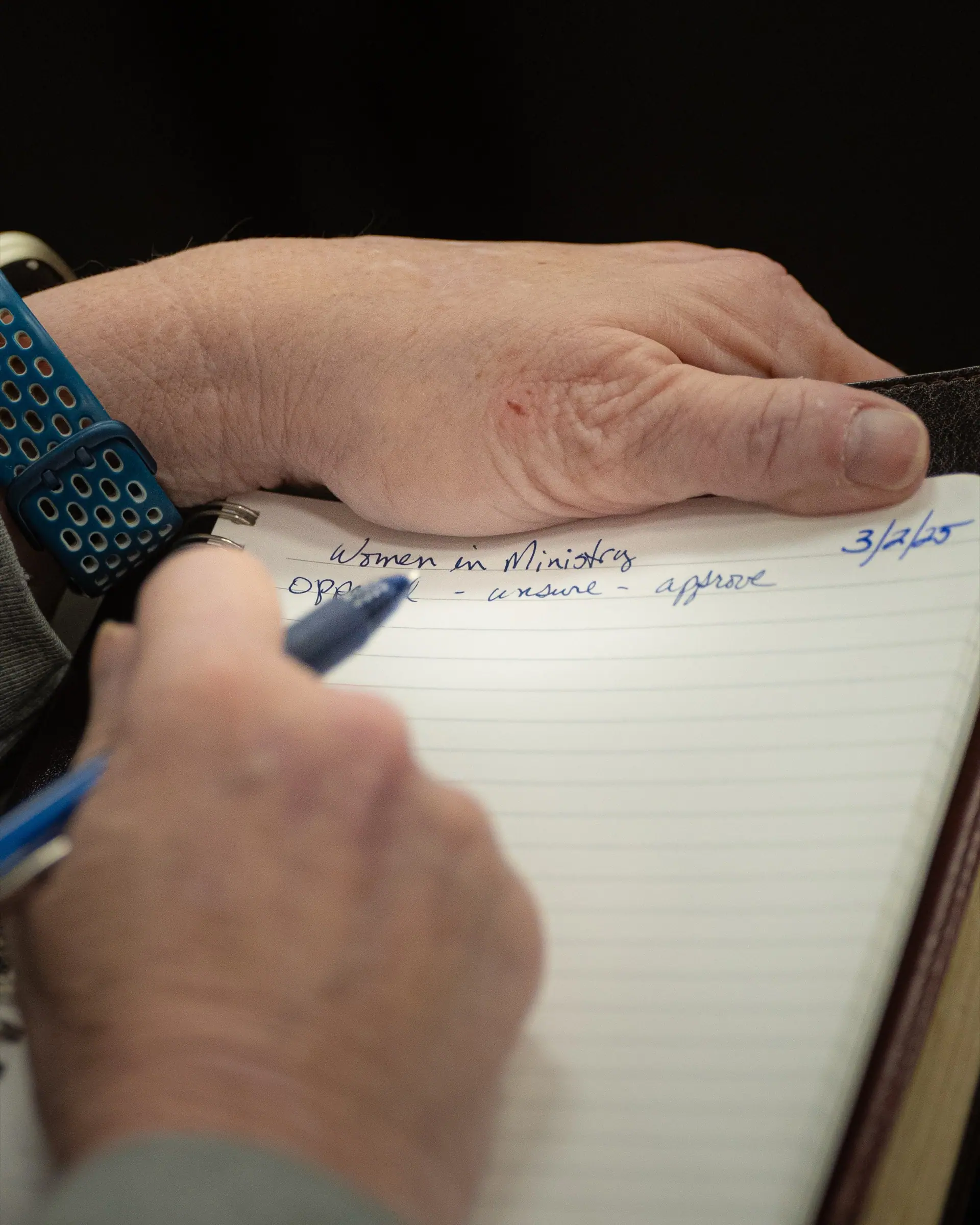 A hand writing notes during the sermon