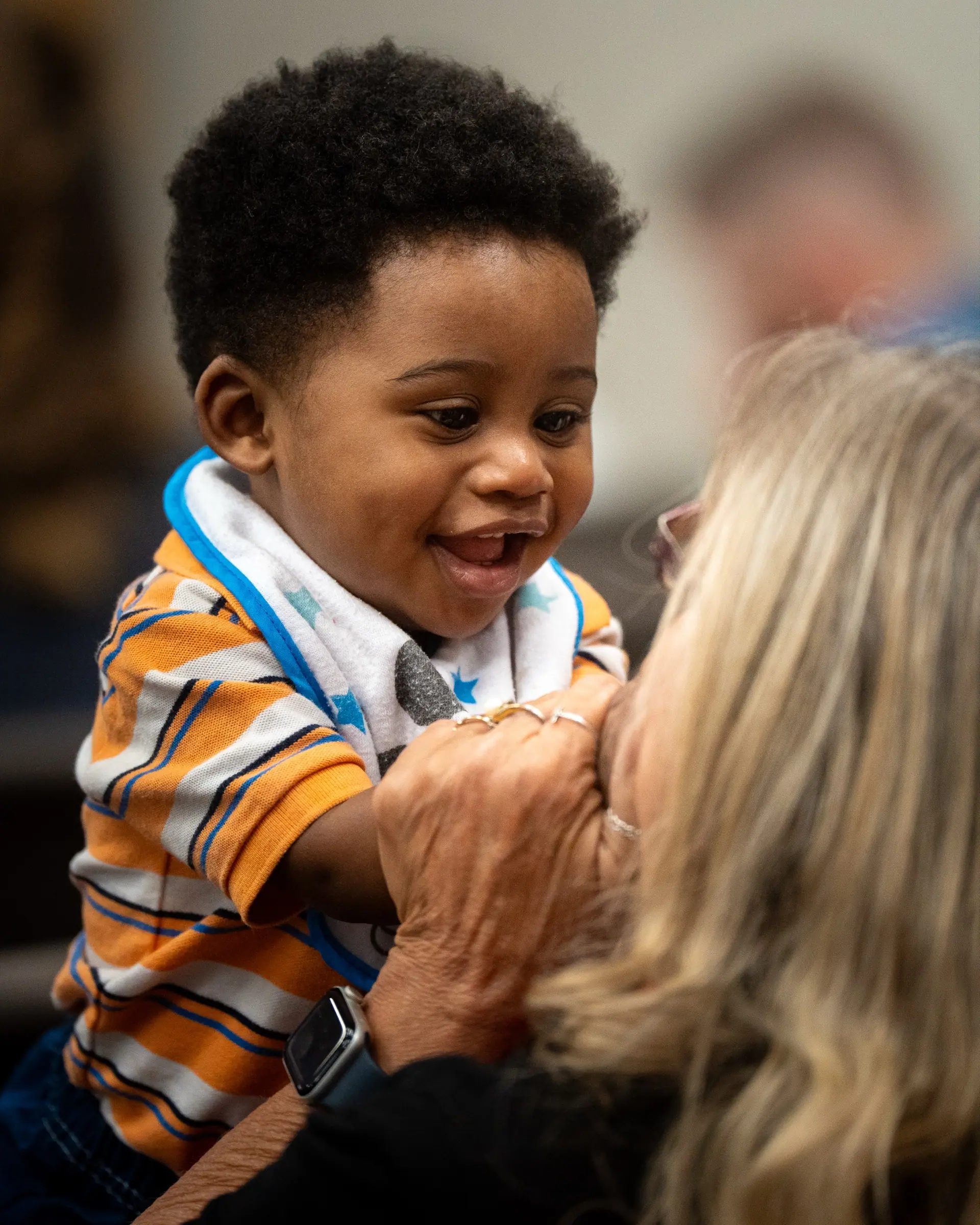 A toddler laughing in the arms of a church member